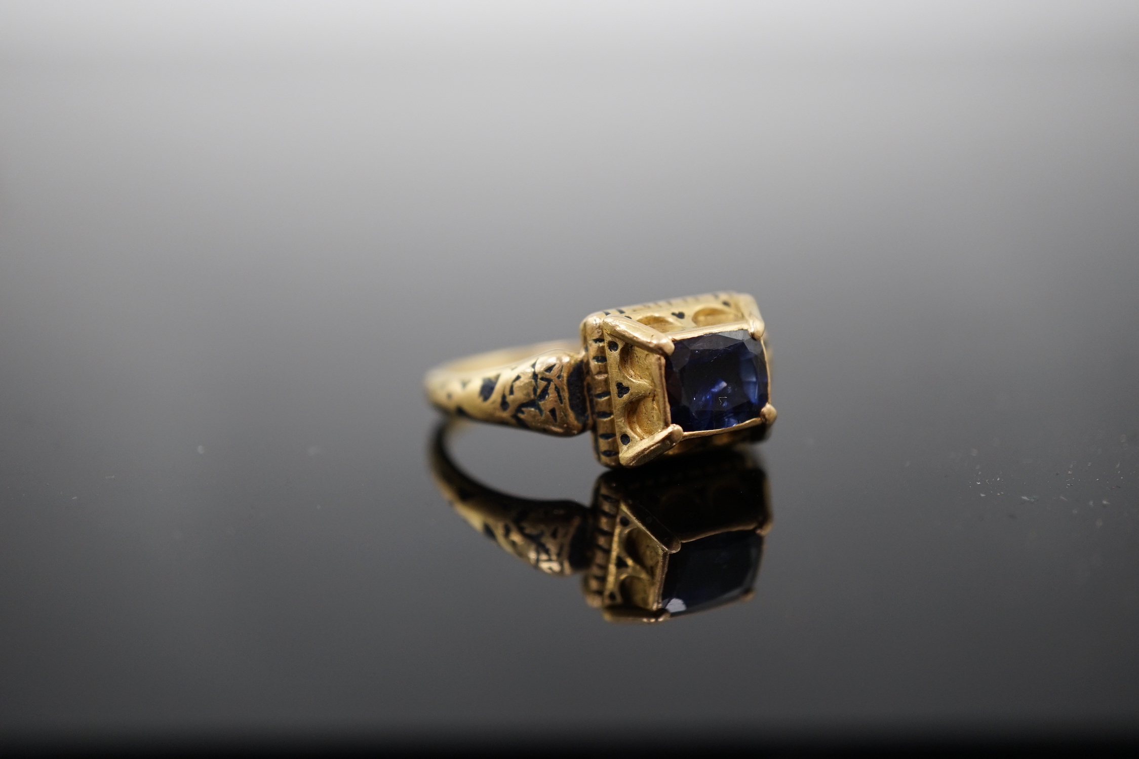 An antique high carat gold, black enamel and collet set cushion cut sapphire set 'poison' ring